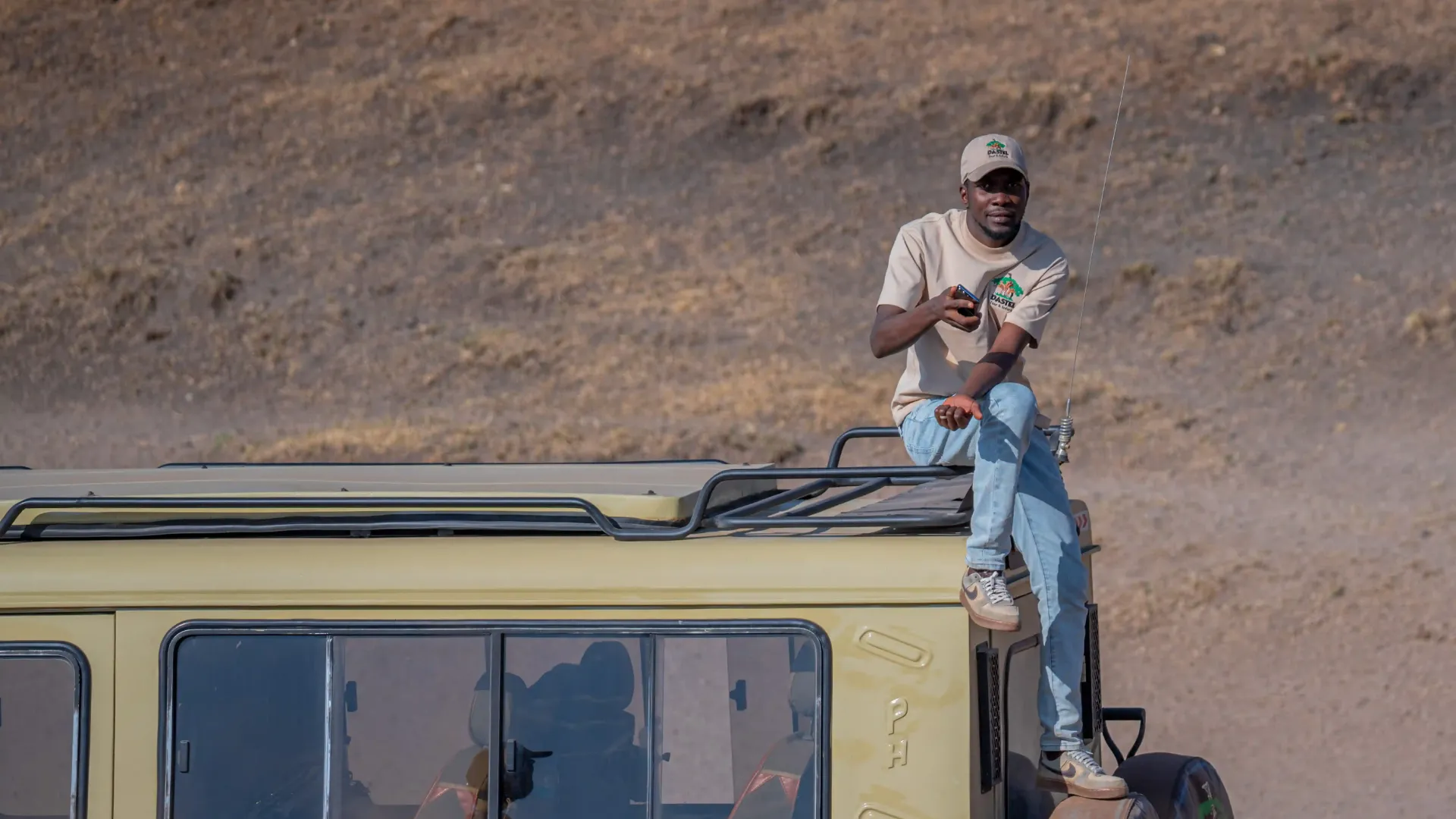 A Dastel Tour and Safaris guide on the roof of a safari vehicle