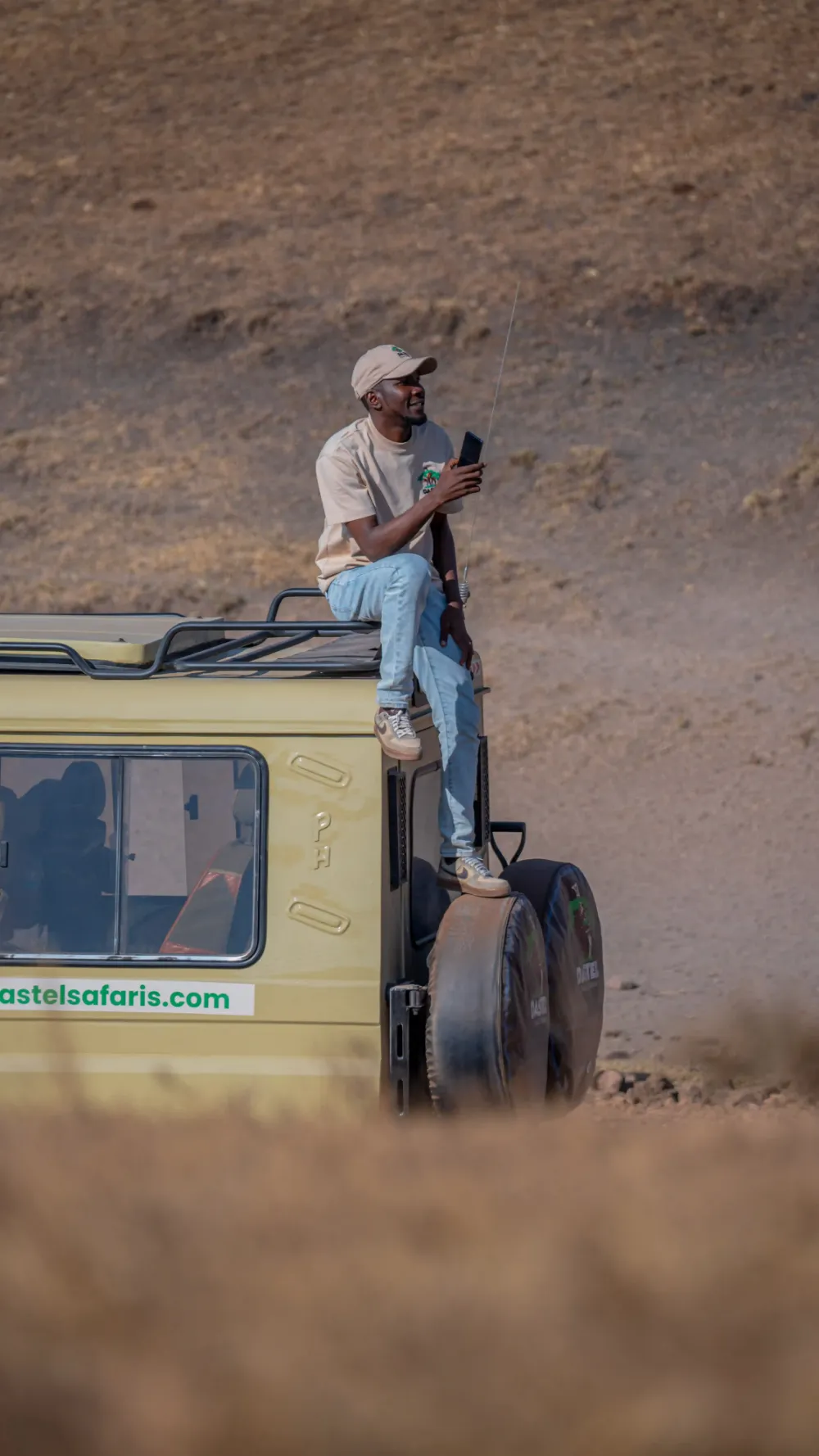 A Dastel Tour and Safaris guide on the roof of a safari vehicle